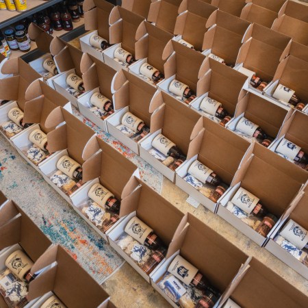 A grid of boxes being filled with sauce and other merchandise for subscription services.