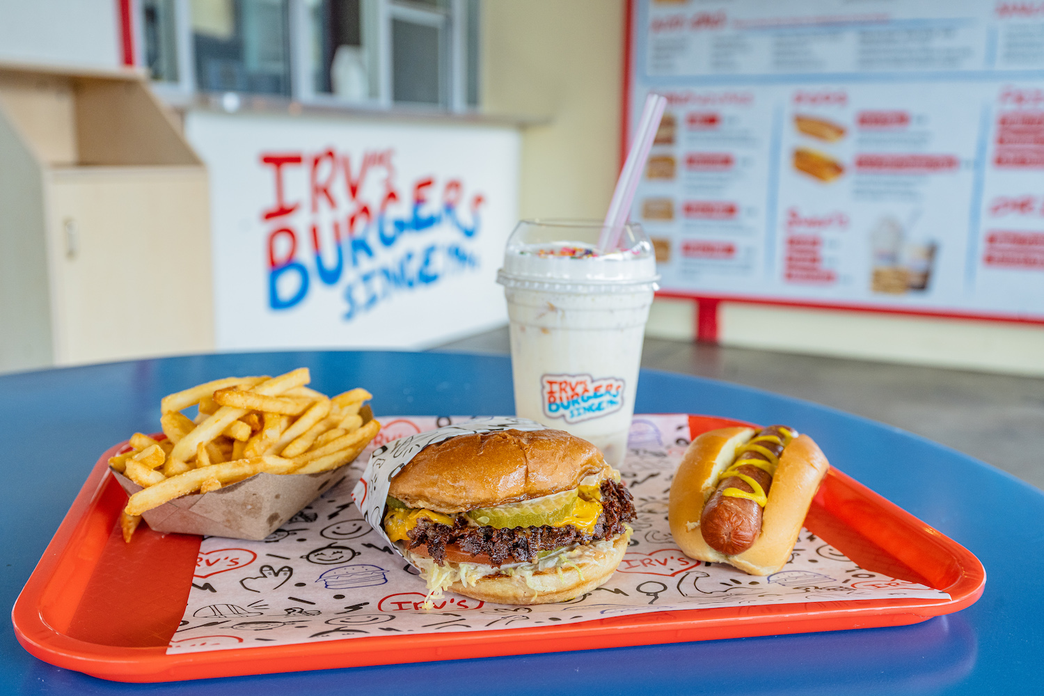 french fries, burger, milkshake and a hot dog on a red food tray