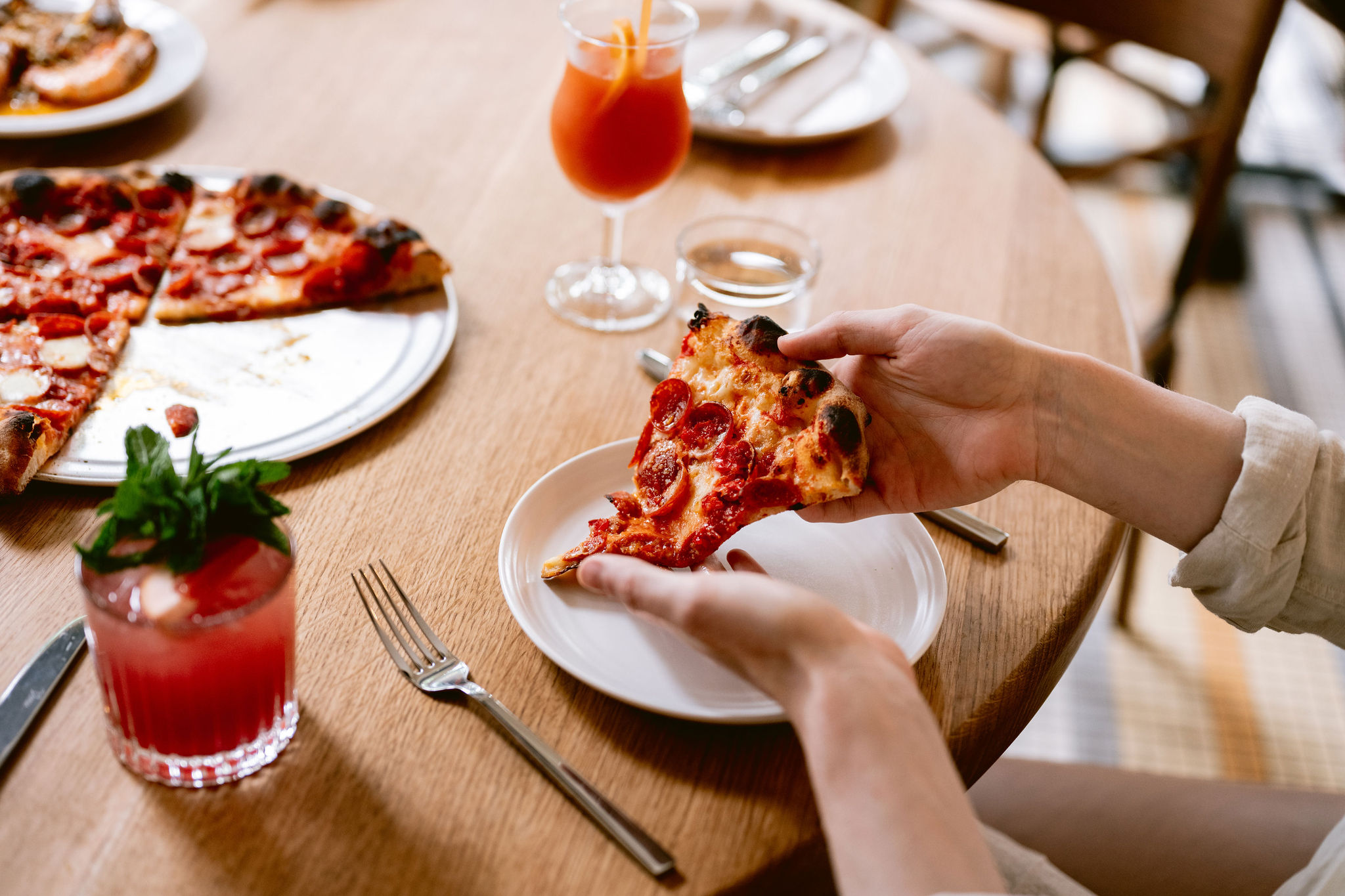 Hand moving a slice of pepperoni pizza to a plate