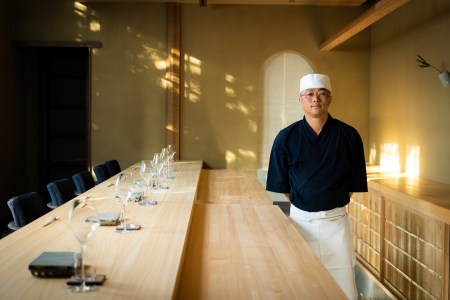 Chef Shingo Akikuni standing next to bar in the restaurant