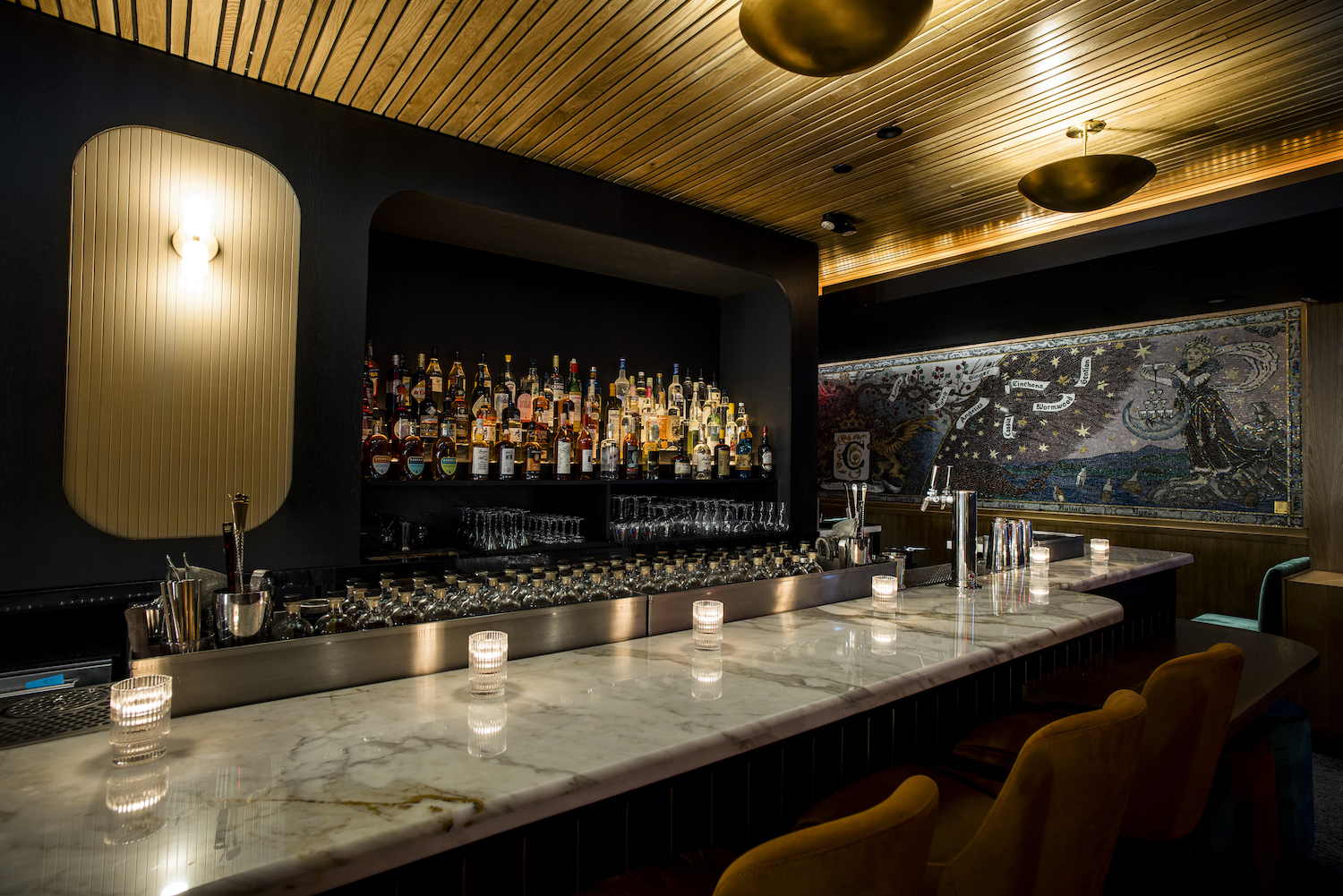 DImly lit marble bar with velvet bar stools