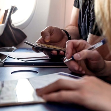 Airplane passengers filling out immigration and customs forms on the plane