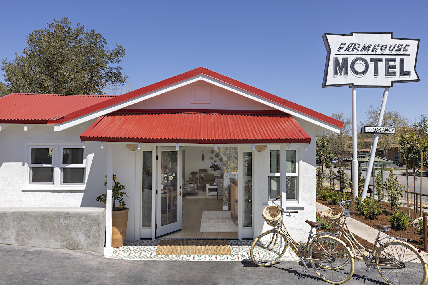 Exterior of the Farmhouse Motel, resembling a small white barn with red details and doors opening to a small living room