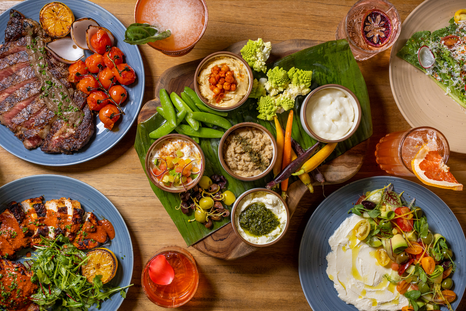 Plates of food including a mezze platter with mezze platters with whipped feta, Calabrian chili prawns, potato zeppole and baba ghanoush