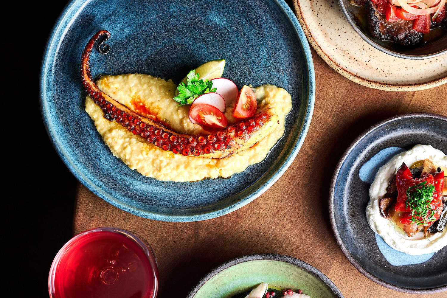 Plated squid tentacle next to other dishes on a table