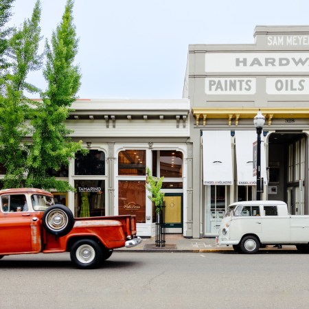 Exterior of row of shops on a street with old cars.