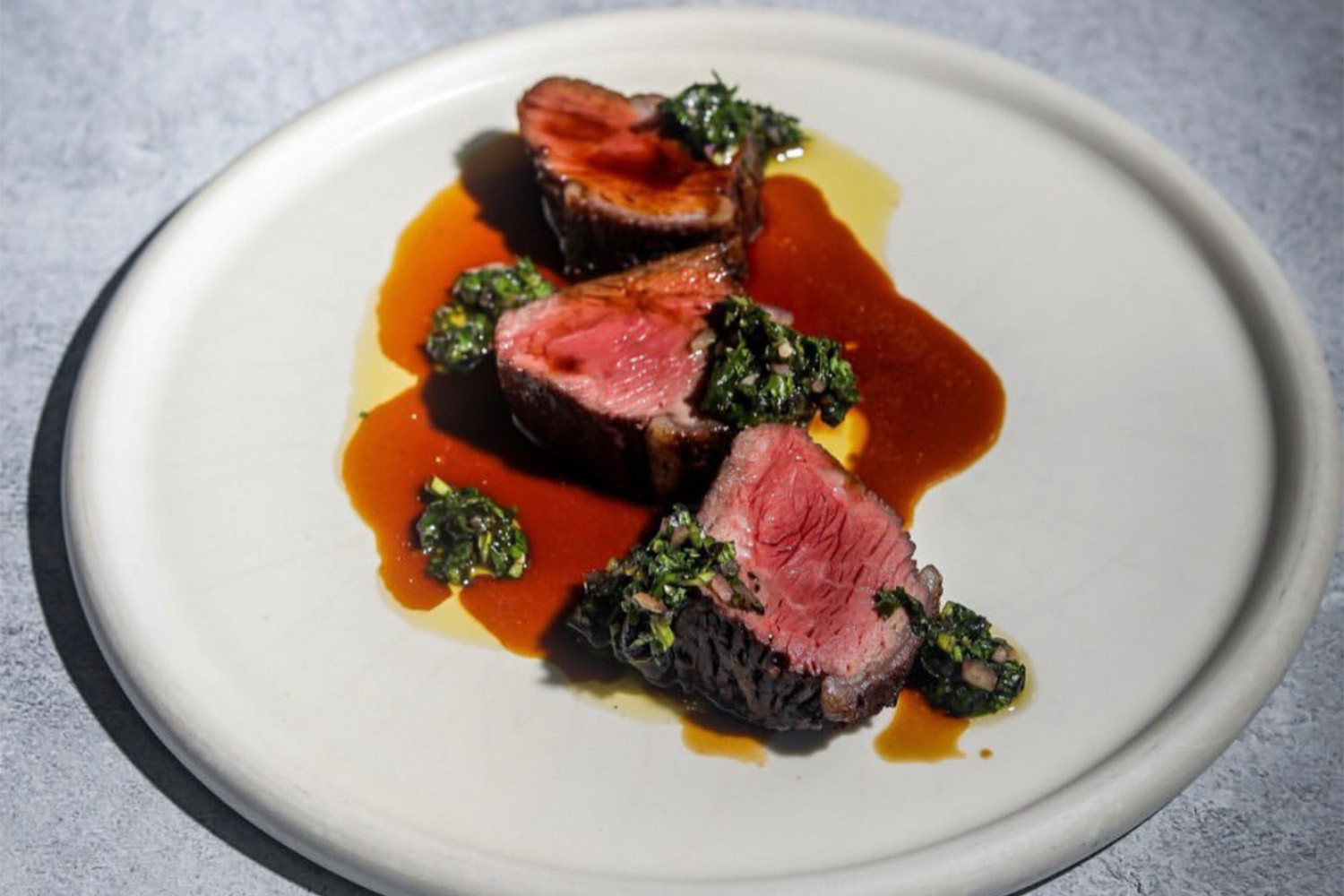 Sliced pieces of steak on a plate with sauce