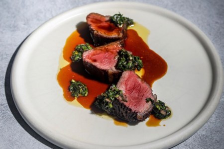 Sliced pieces of steak on a plate with sauce