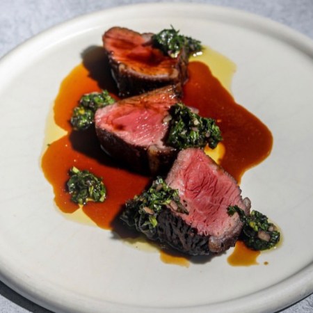 Sliced pieces of steak on a plate with sauce