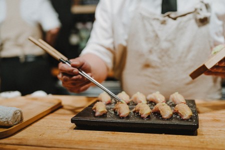 Sushi on a board being arranged with chopsticks by a chef with Sushi by Scratch