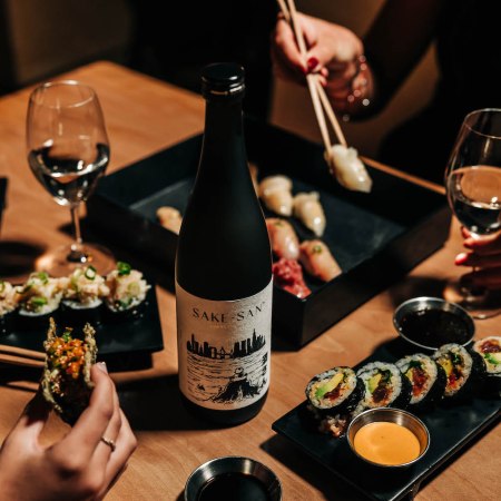 Sushi, wine glasses and a bottle of sake on a table