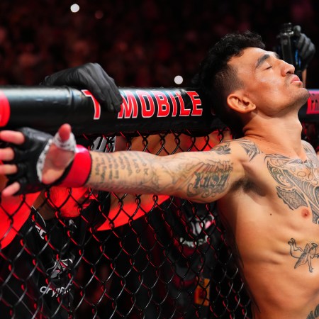 A photo of Max Holloway in the UFC Octagon with his arms spread out to either side.