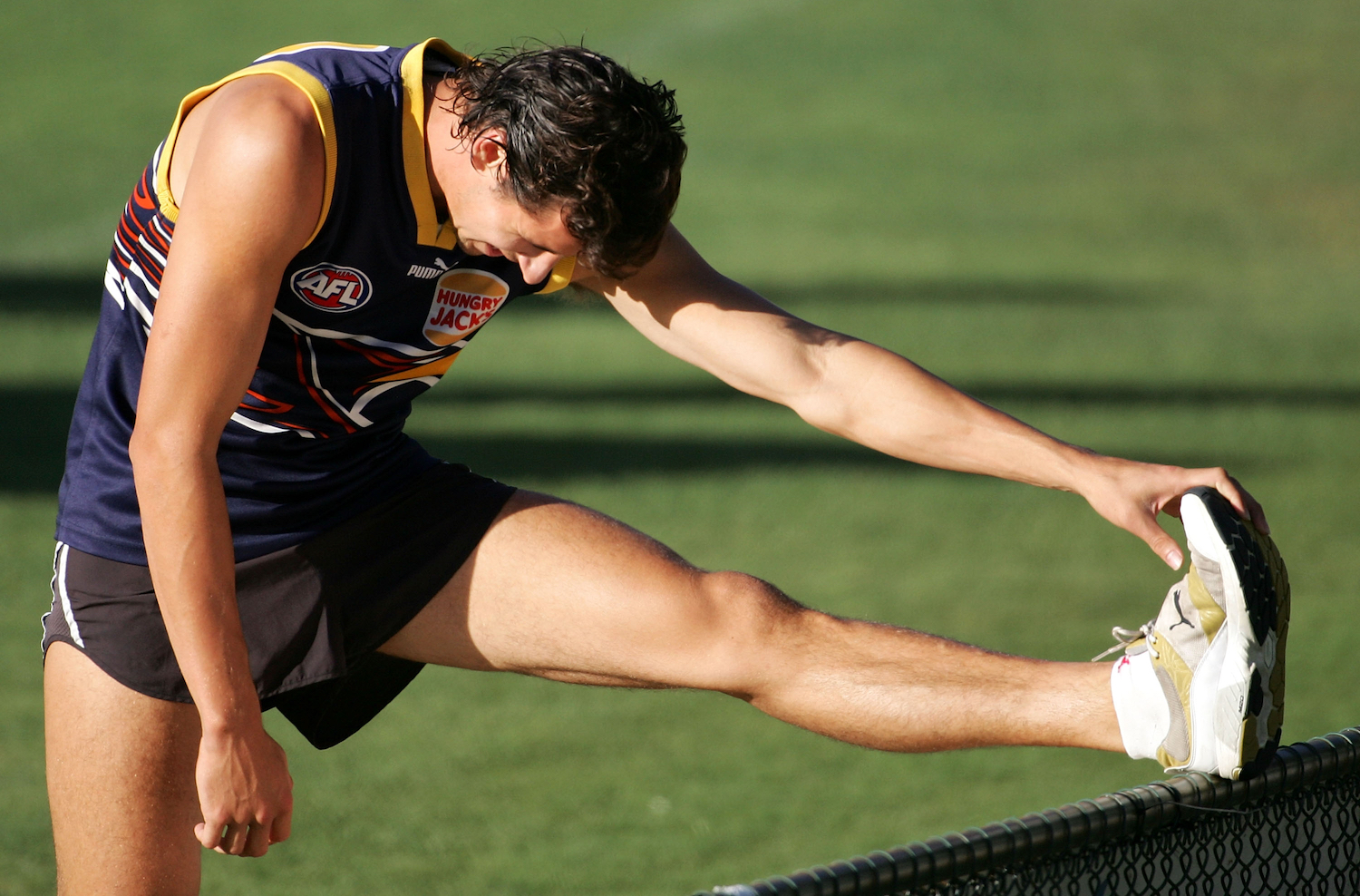 A muscular rugby player stretching.