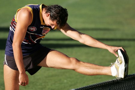 A muscular rugby player stretching.