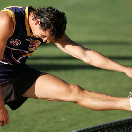 A muscular rugby player stretching.