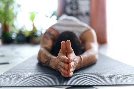A man practicing mat Pilates in order to elongate his spine.