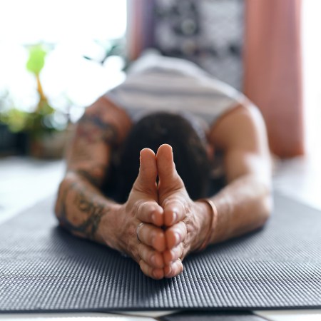 A man practicing mat Pilates in order to elongate his spine.