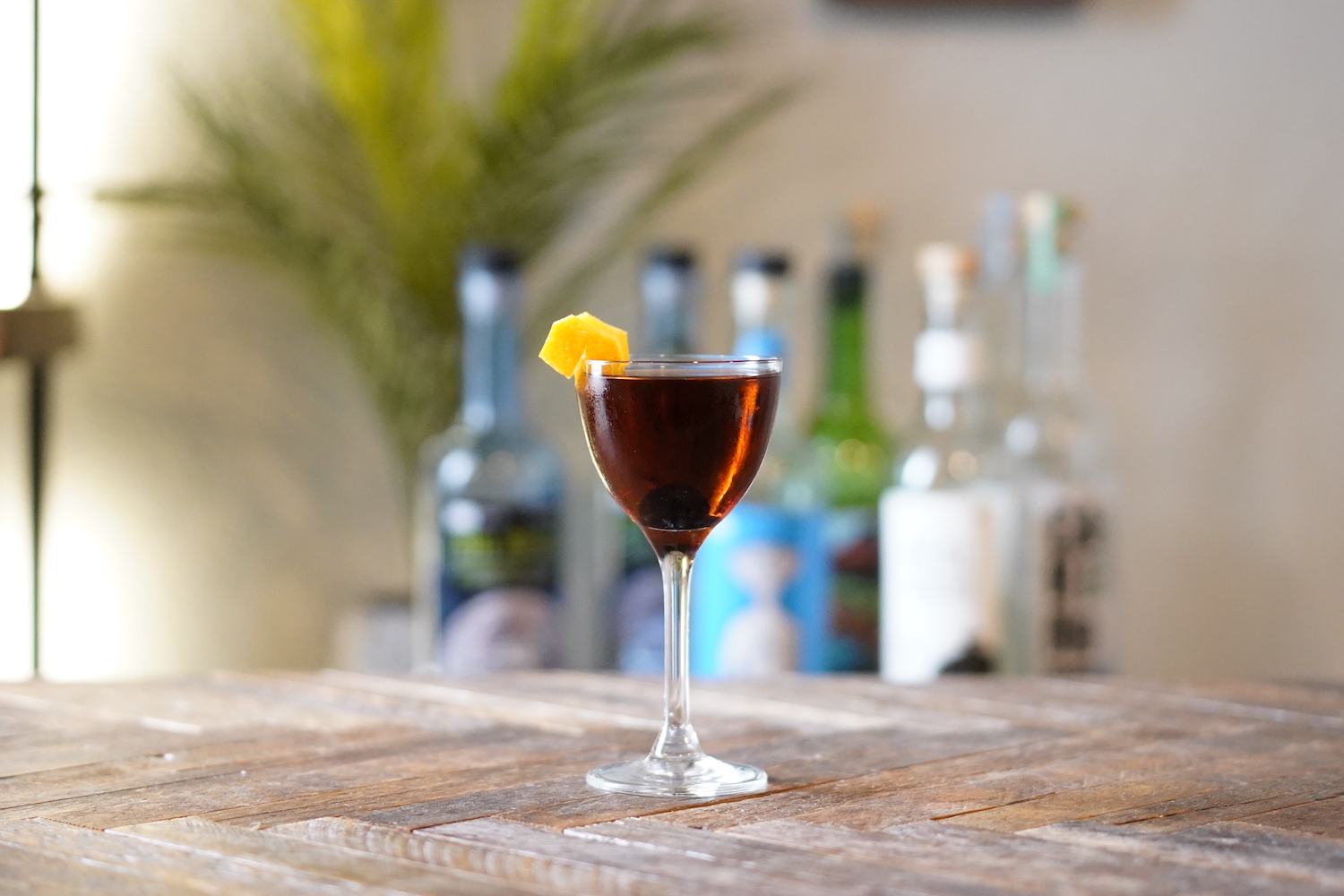 a tequila manhattan in a nick and nora glass on a wooden table
