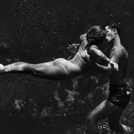 a black and white photo of a man and woman kissing under water