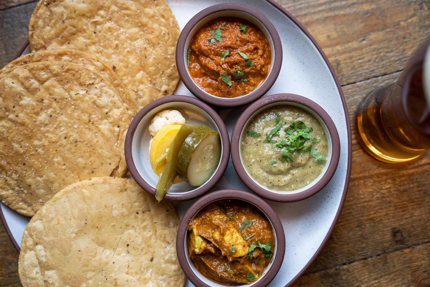trio of salsas with pickles and corn tostadas on a wooden table