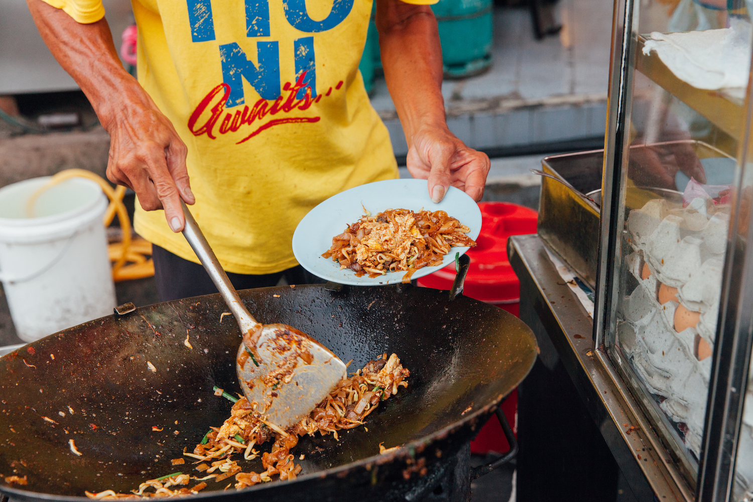 Hands of the senior man cooking kway teow noodles at the street market, Penang, Malaysia