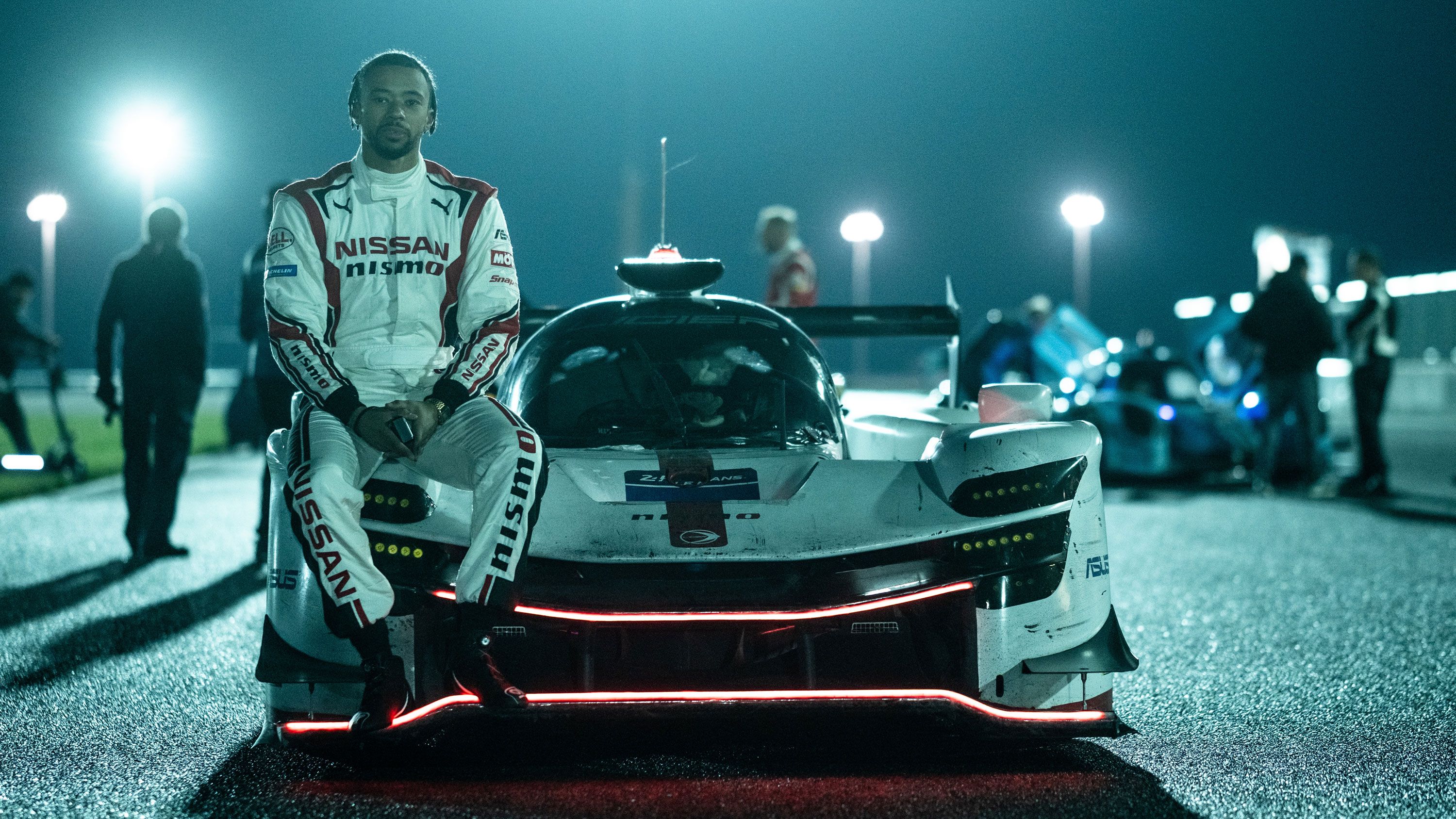 A picture of Jann Mardenborough sitting against his racecar.