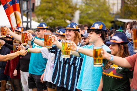 Group of people holding out mugs of beer