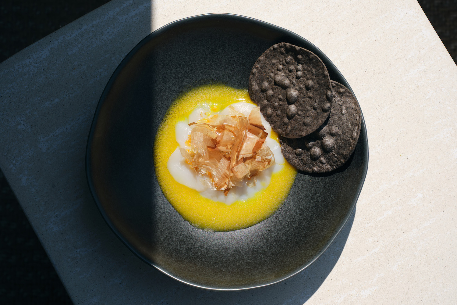 Scallop Aguachile on a black plate with blue corn tortillas