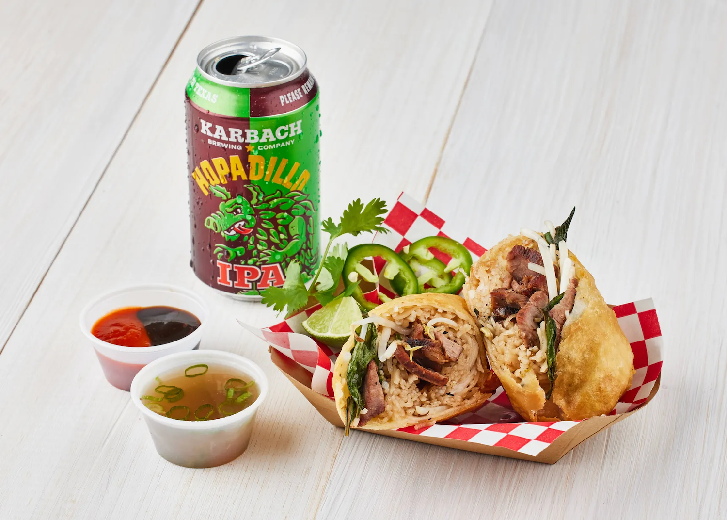 Deep fried pho in a container next to sauces and a can of IPA