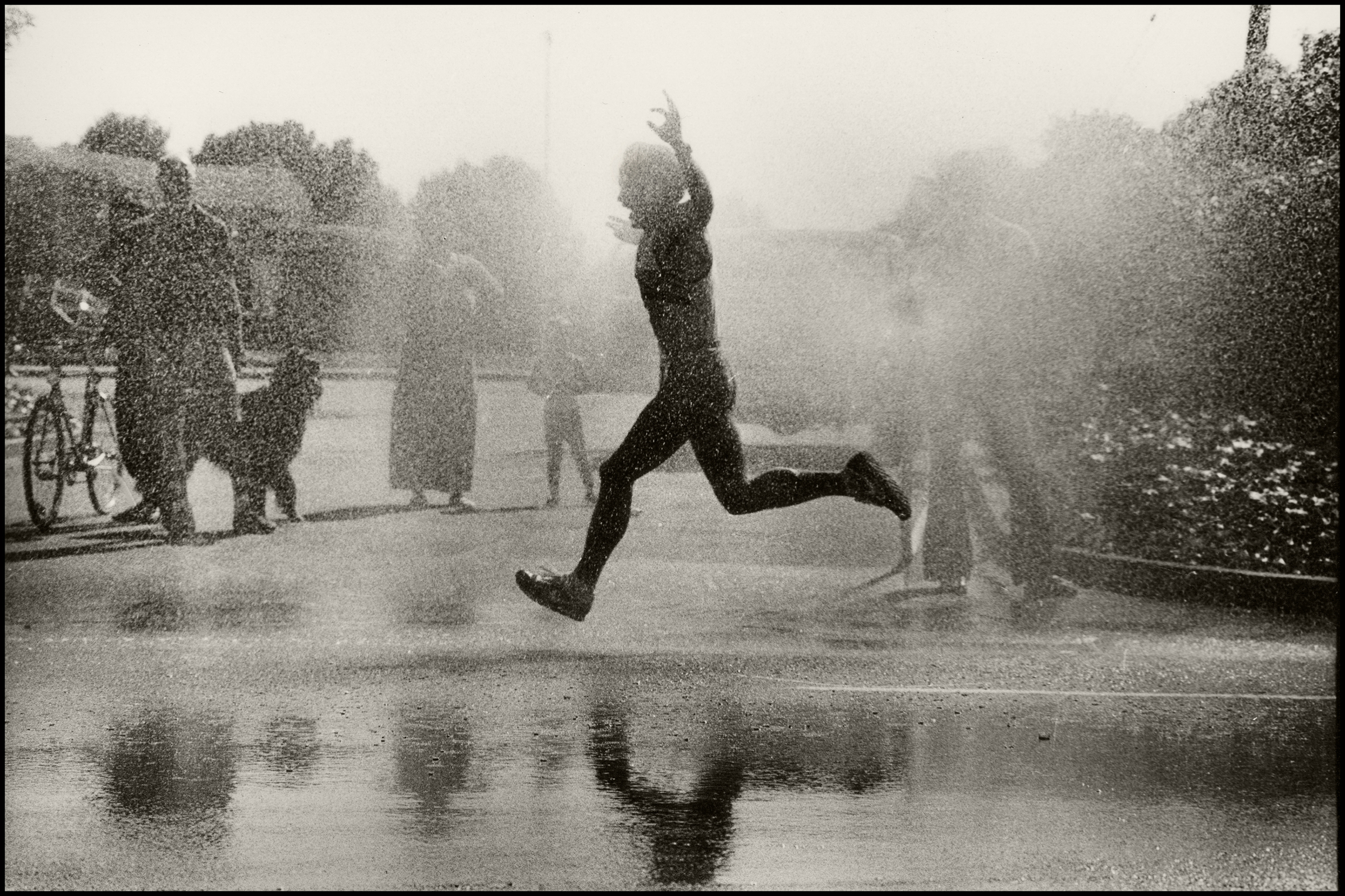 A man running through water in a race with his hands stretched in joy.