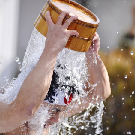 A man pours cold water on his head from a bucket.