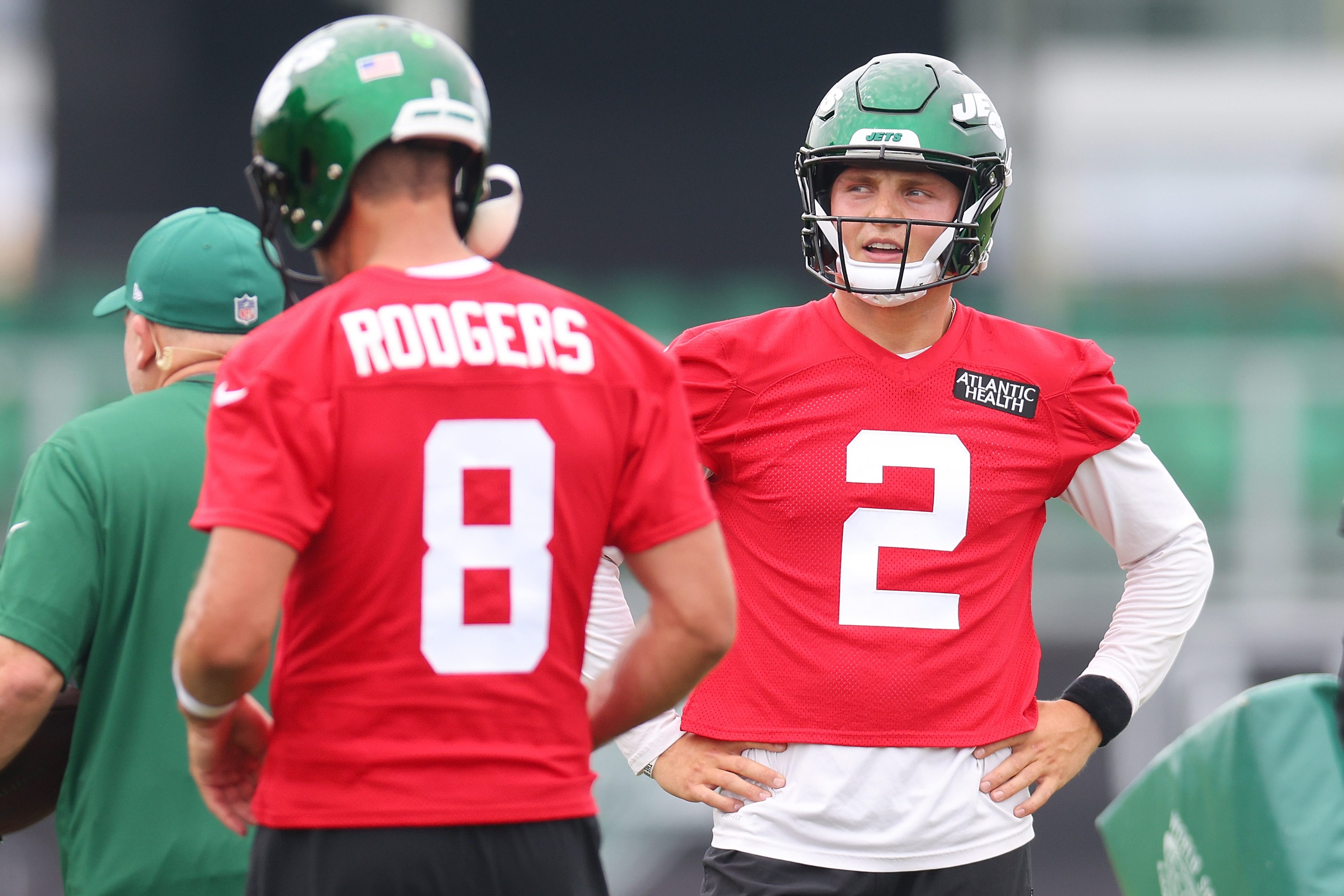 Aaron Rodgers and Zach Wilson run drills during training camp.