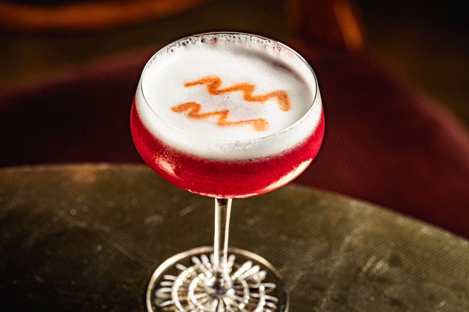 Pink cocktail in coupe glass with bitters on top