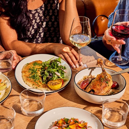 People sitting around the table with plates of food and wine
