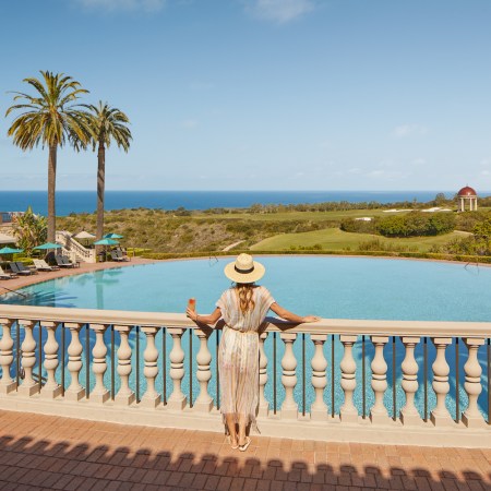 Woman standing on a terrace looking over the Coliseum Pool at the Resort at Pelican Hill