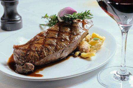 Steak and potatoes on a plate with red wine
