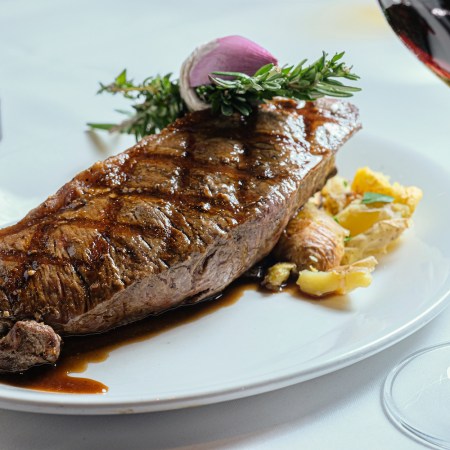 Steak and potatoes on a plate with red wine
