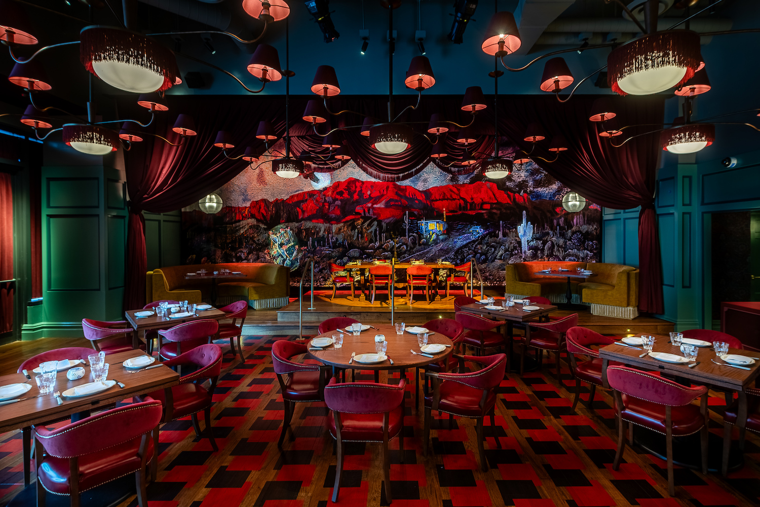 Room with a stage and red seating and interior design, large tables and cushioned chairs