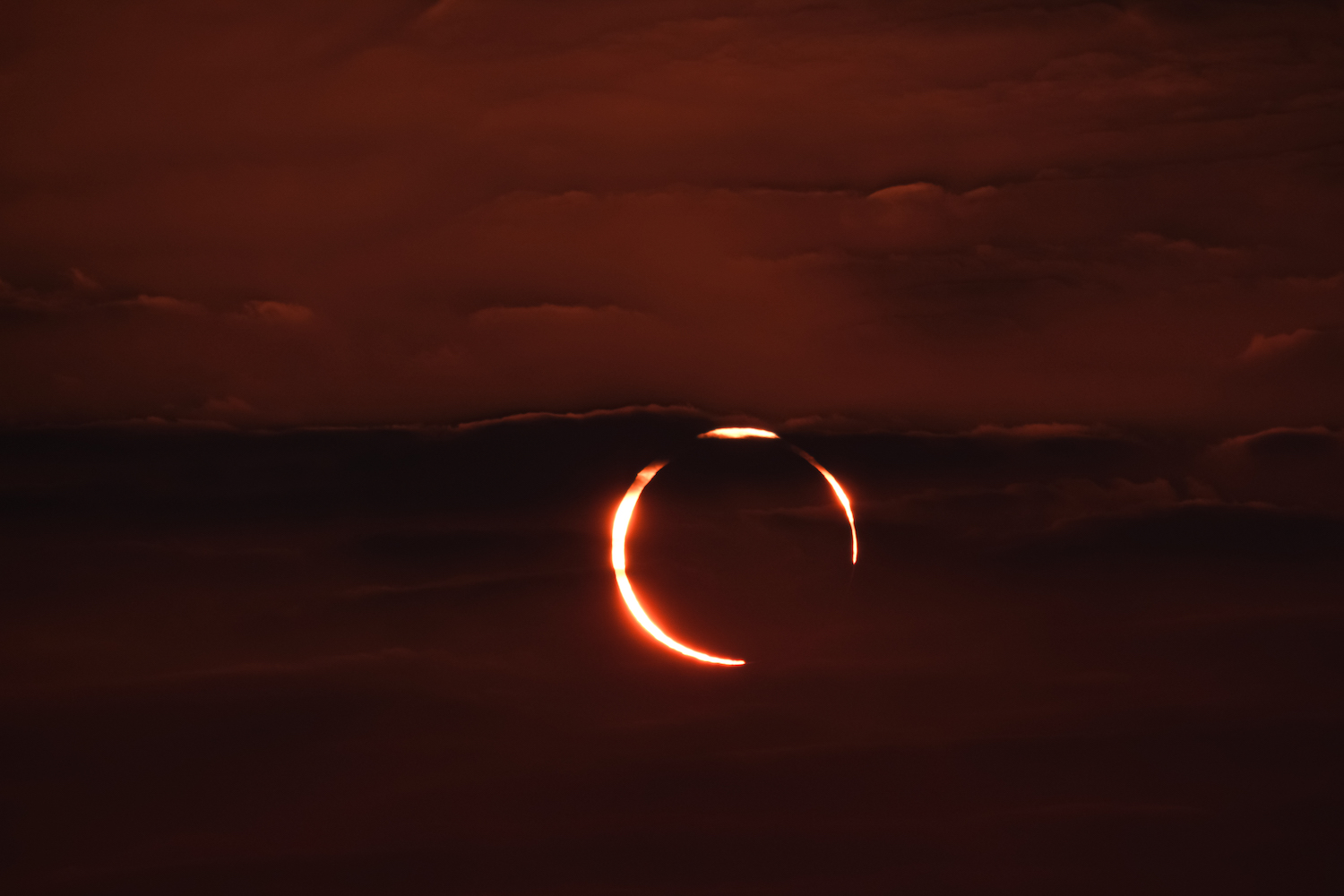 Moon in front of the sun creating red hue in the sky