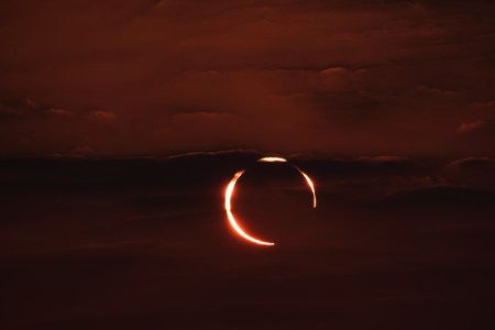 Moon in front of the sun creating red hue in the sky