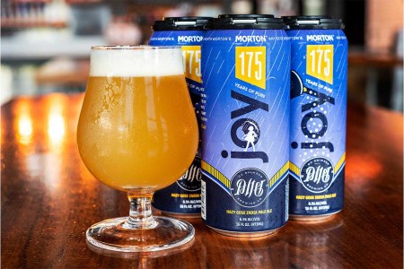 A glass and four cans of Pure Joy, a collaboration between Morton Salt and Alter Brewing