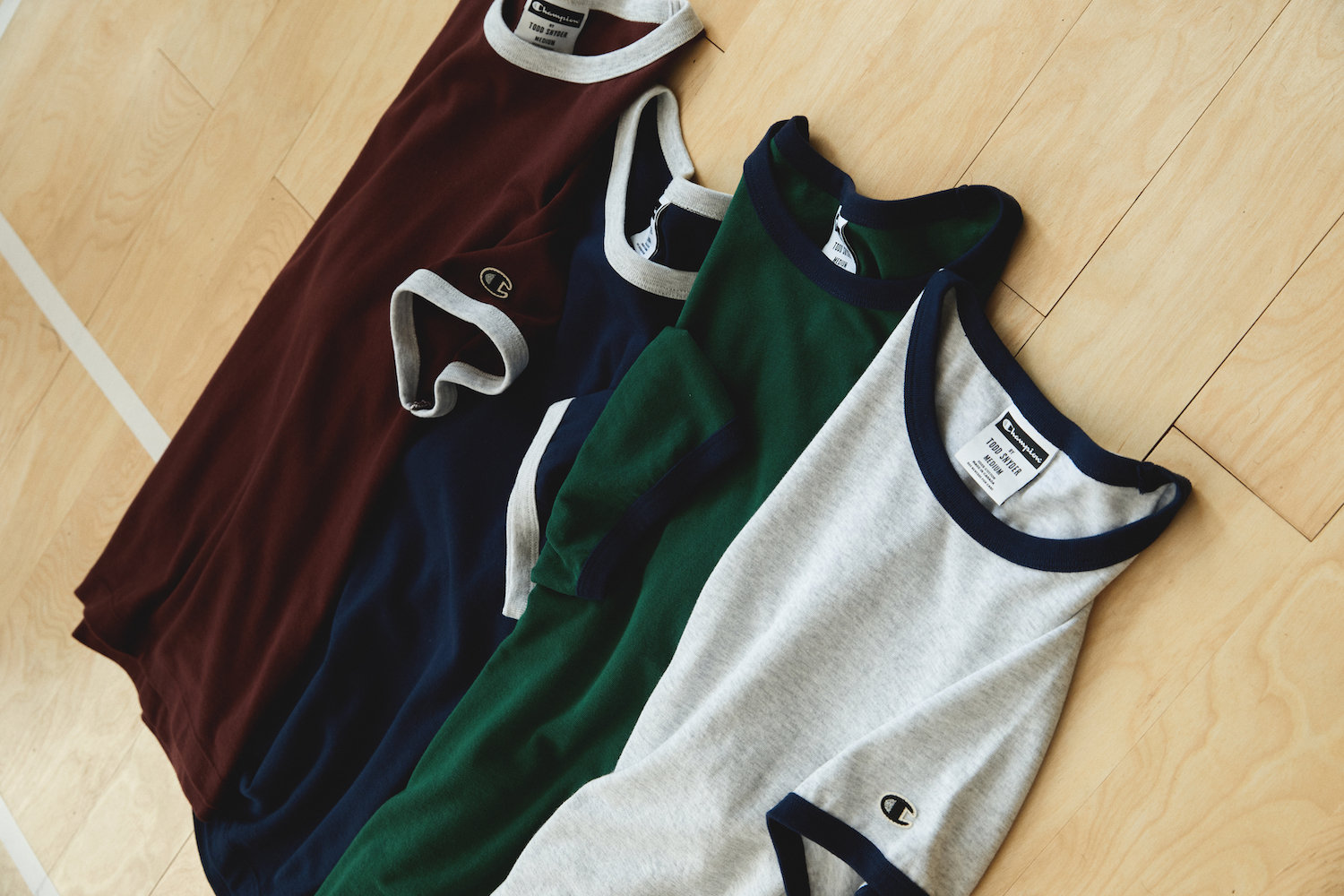 a collage of shirts from Todd Snyder + Champion on a hardwood background