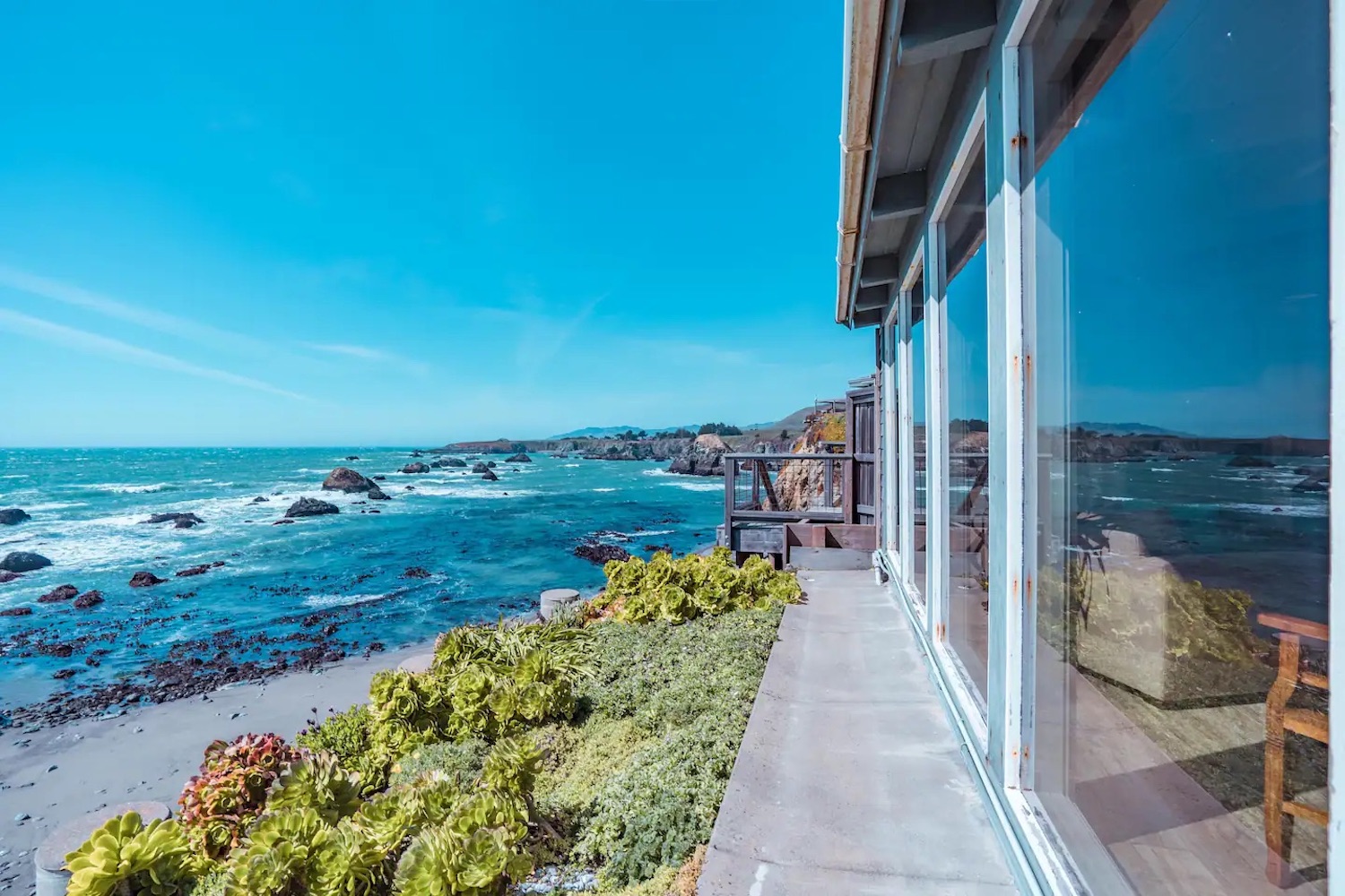 Exterior of house with floor-to-ceiling windows right on the beach facing the ocean