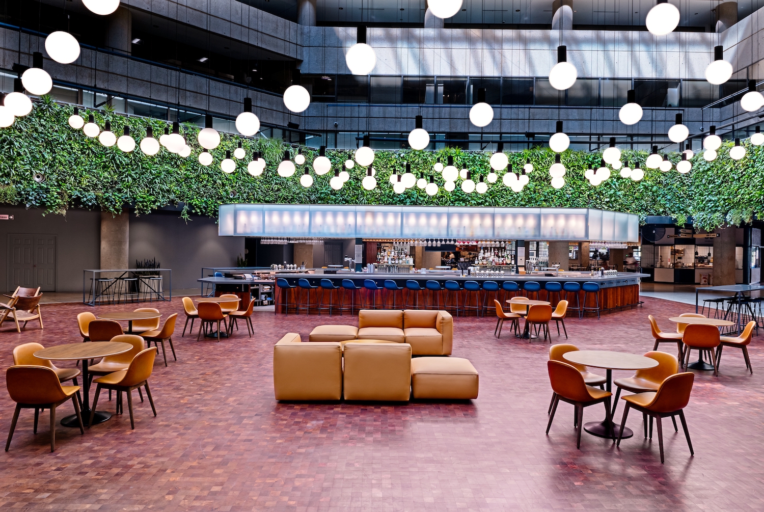 Interior of The Square with cushioned chairs, a circular bar and string lighting
