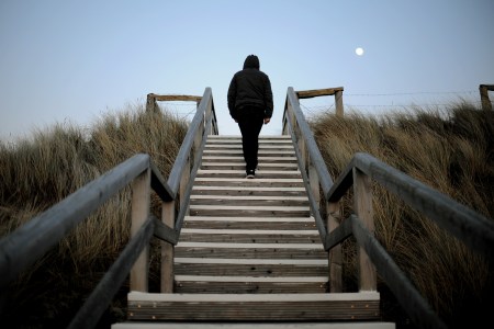 A man walks up the steps on a flight of stairs at a beach.