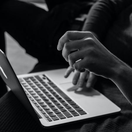 An employee typing at a laptop in black and white. Shallow work is interfering with productive "deep work."
