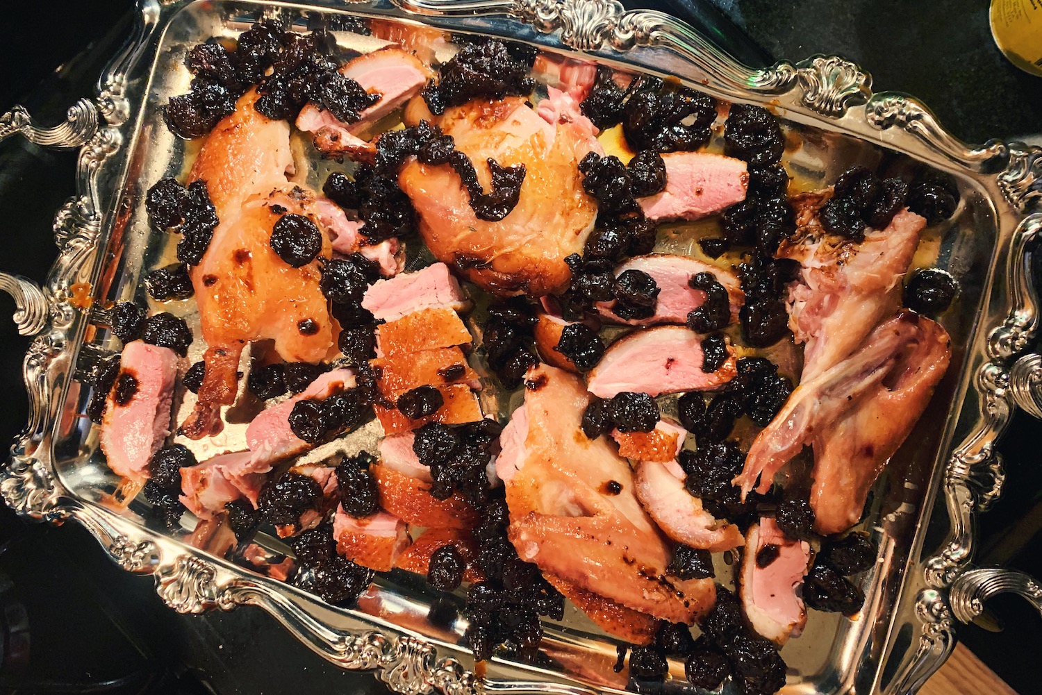 roasted duck on a silver platter with cherry jus