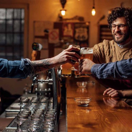 A group of friends drinking beer at a local pub and having a conversation with the bartender