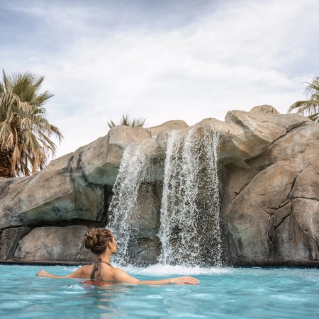 Lady in a pool looking at water fixture