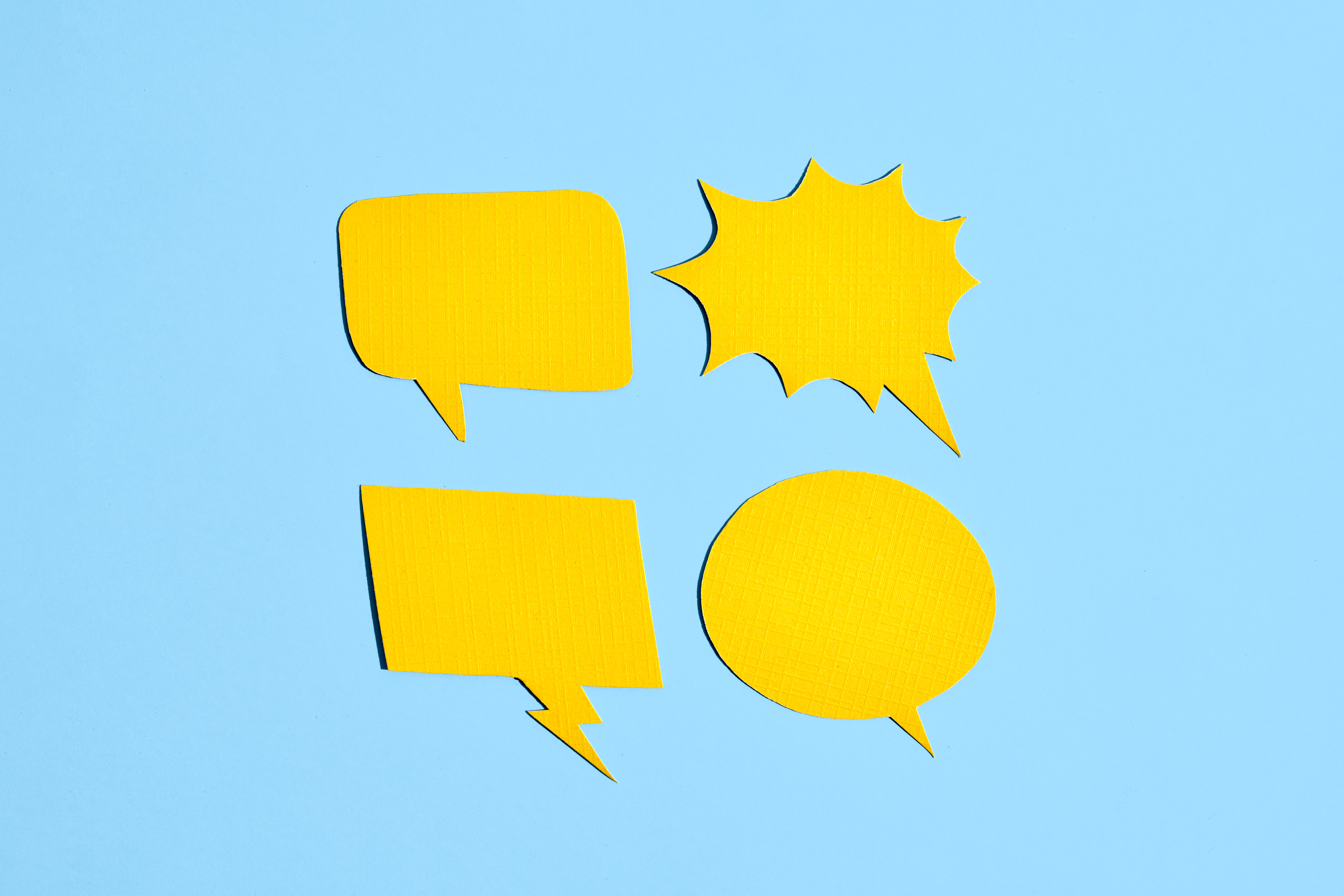 Four yellow comic book voice bubbles against a light blue background.